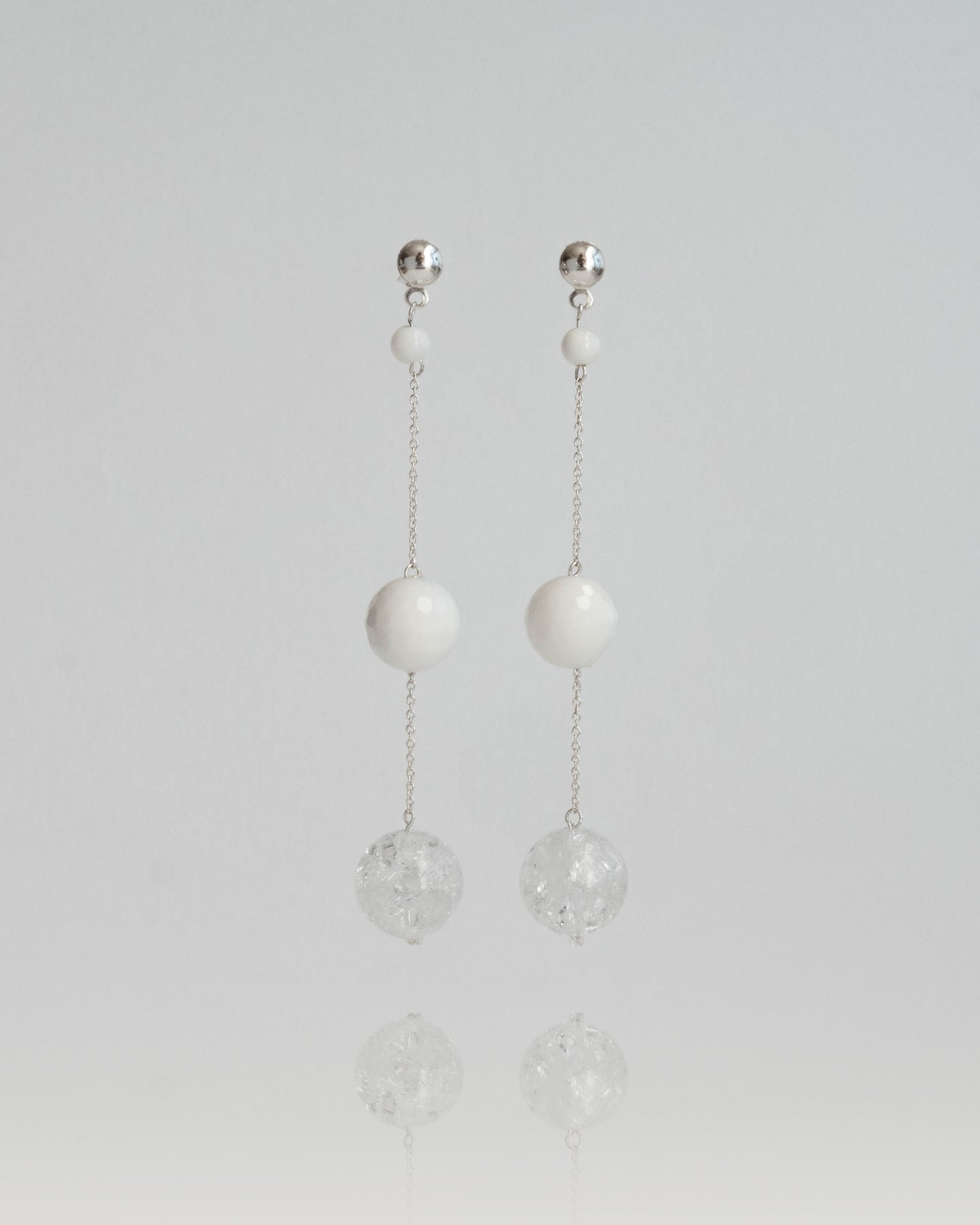 Delicate chain earrings featuring luminous Clear Quartz and soft White Coral, suspended from silver chains with hooks, 8 cm in length.