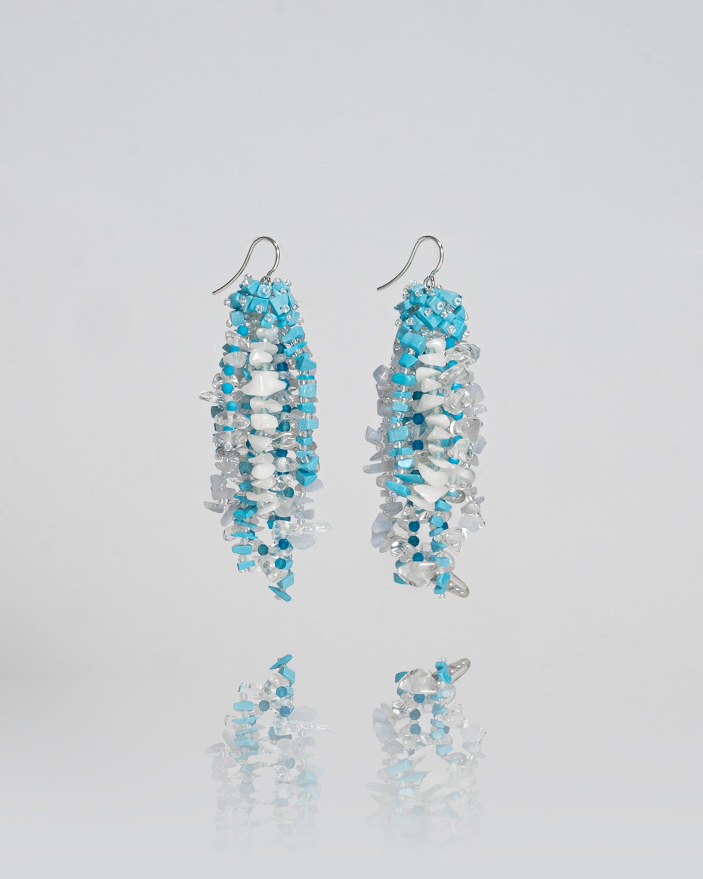 Mixed gemstones earrings featuring topaz, apatite, turkenite, chalcedony, and quartz stones with silver hooks, 8 cm in length.