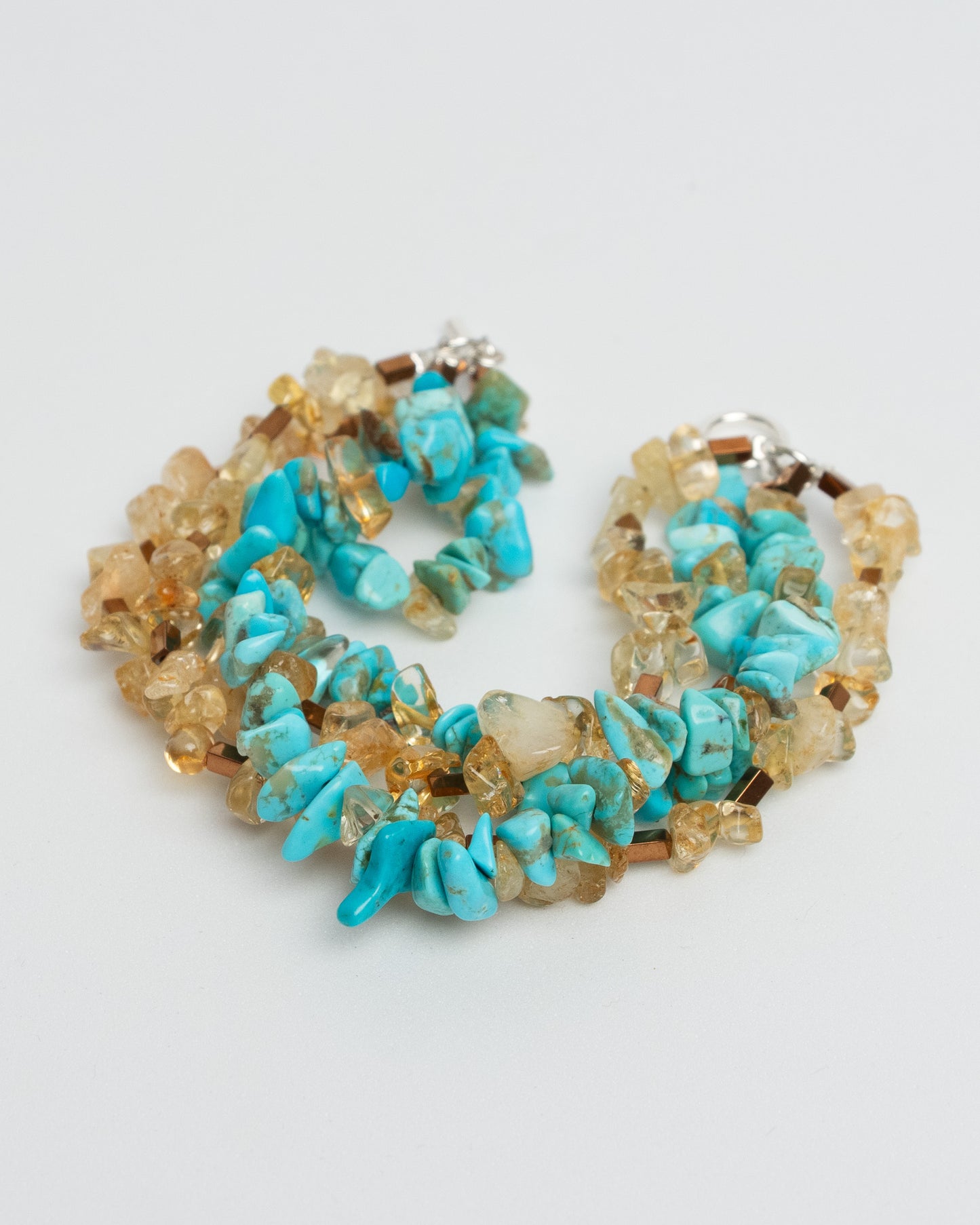 Layered gemstone bracelet for women featuring four chunky strands of natural turquoise, sunstone, and hematite beads. Multicolor summer statement bracelet with sterling silver T-bar clasp. Handmade multistrand accessory, bold and colorful jewelry inspired by Mediterranean style. One of a kind, artisanal, natural gemstone jewelry for a curated boho or elegant outfit.