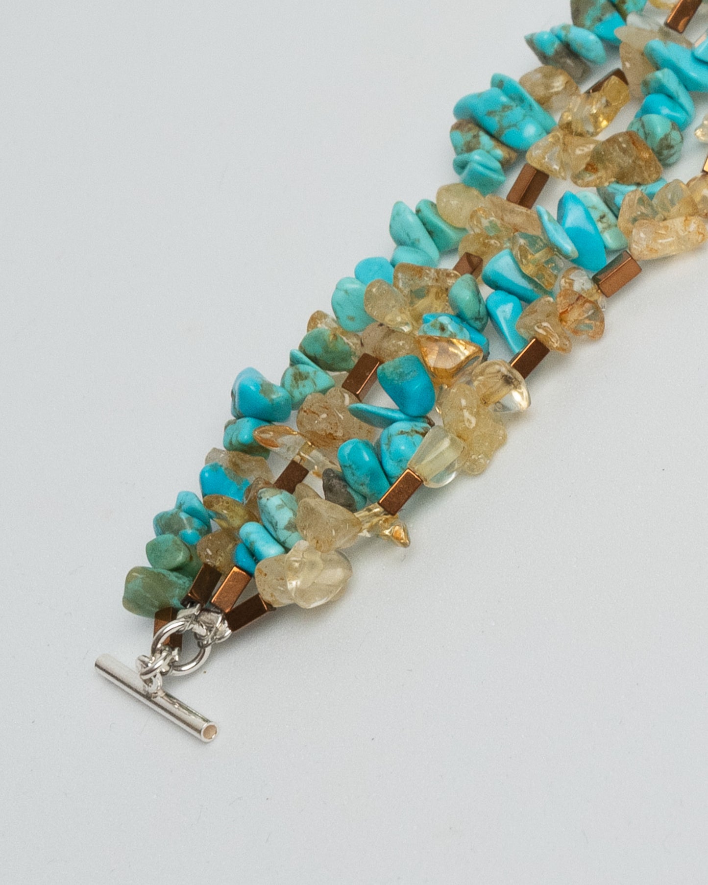 Layered gemstone bracelet for women featuring four chunky strands of natural turquoise, sunstone, and hematite beads. Multicolor summer statement bracelet with sterling silver T-bar clasp. Handmade multistrand accessory, bold and colorful jewelry inspired by Mediterranean style. One of a kind, artisanal, natural gemstone jewelry for a curated boho or elegant outfit.