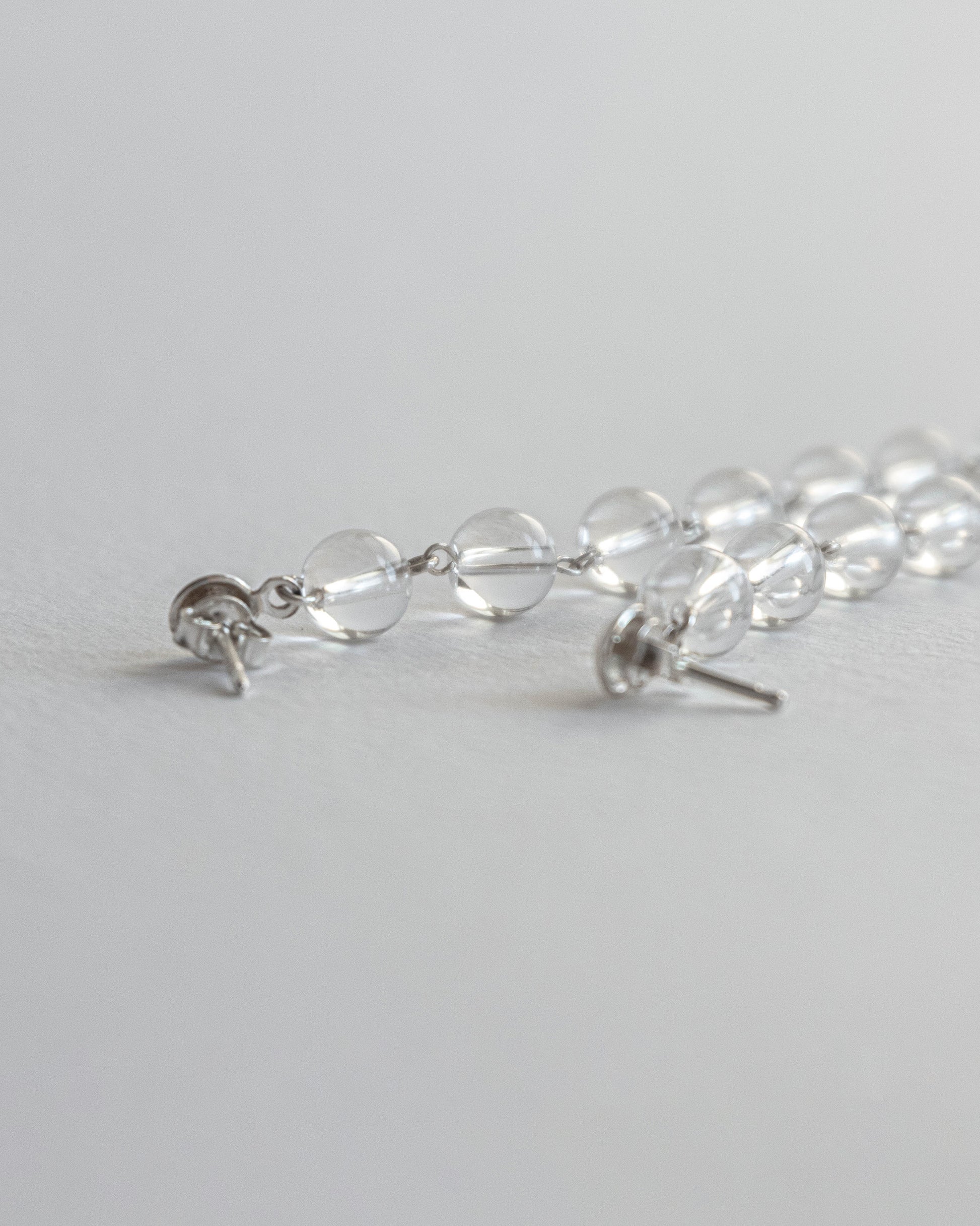 Cascading clear quartz earrings featuring transparent quartz beads in a cascading design with silver studs, 6 cm in length.