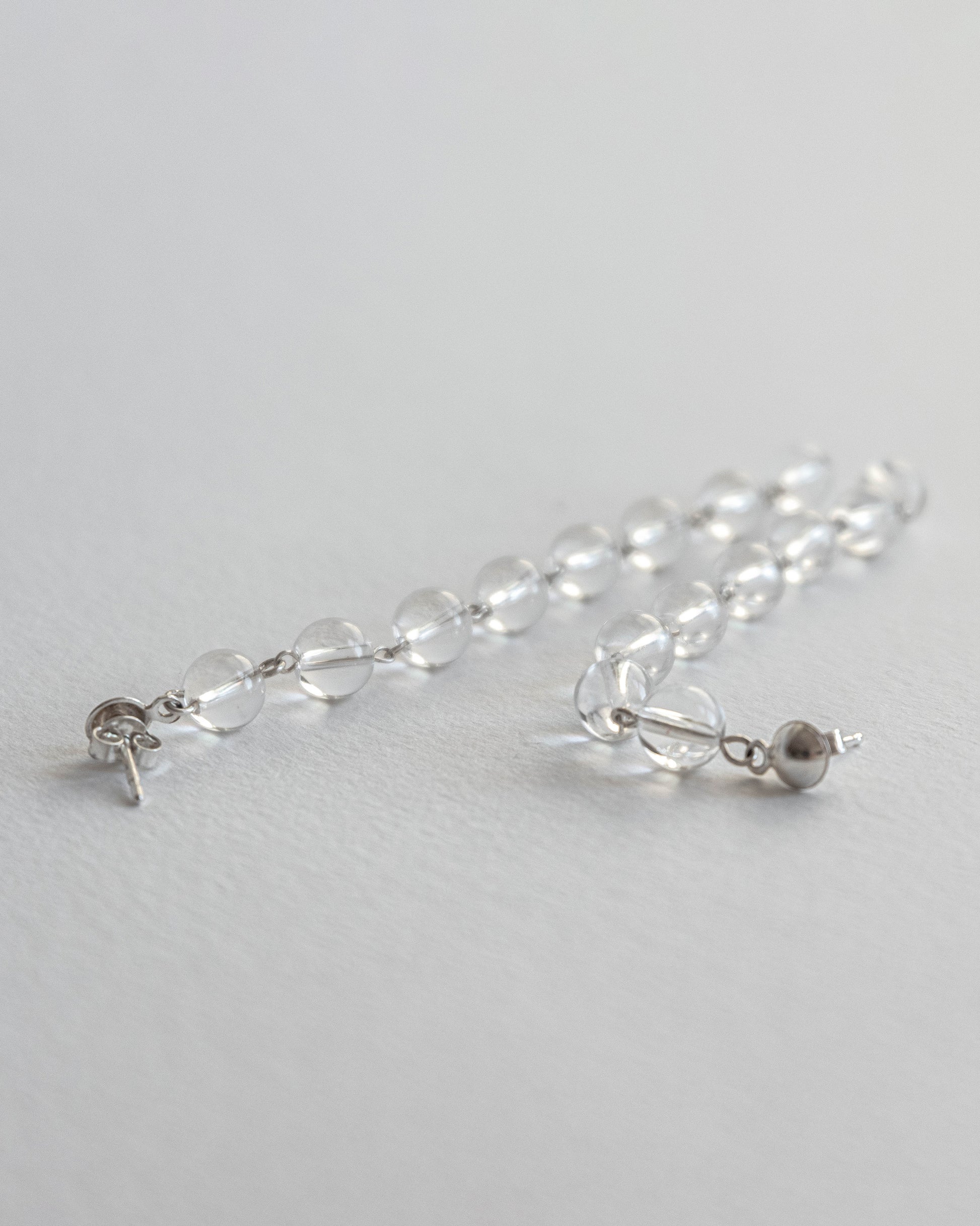 Cascading clear quartz earrings featuring transparent quartz beads in a cascading design with silver studs, 6 cm in length.