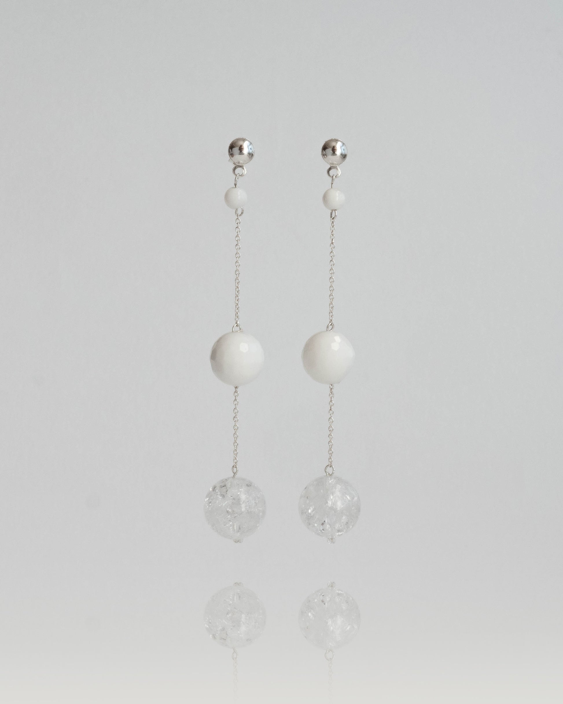 Delicate chain earrings featuring luminous Clear Quartz and soft White Coral, suspended from silver chains with hooks, 8 cm in length.