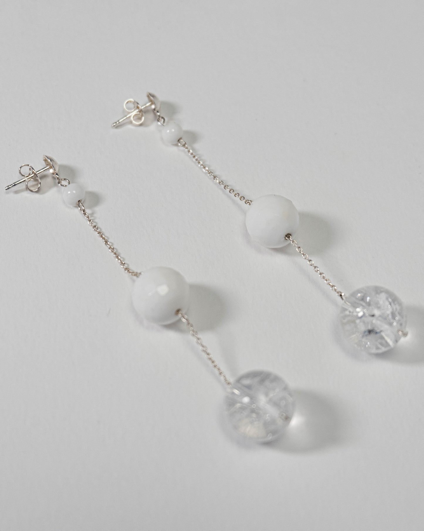 Delicate chain earrings featuring luminous Clear Quartz and soft White Coral, suspended from silver chains with hooks, 8 cm in length.