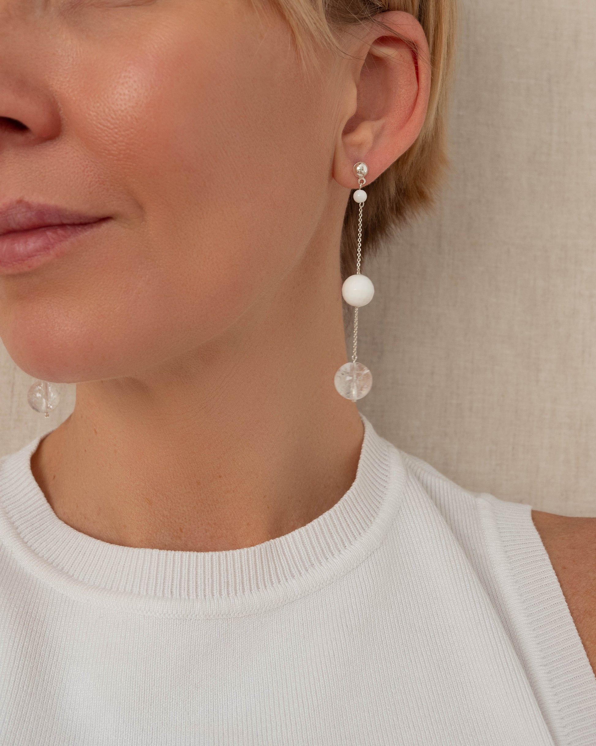 Delicate chain earrings featuring luminous Clear Quartz and soft White Coral, suspended from silver chains with hooks, 8 cm in length.