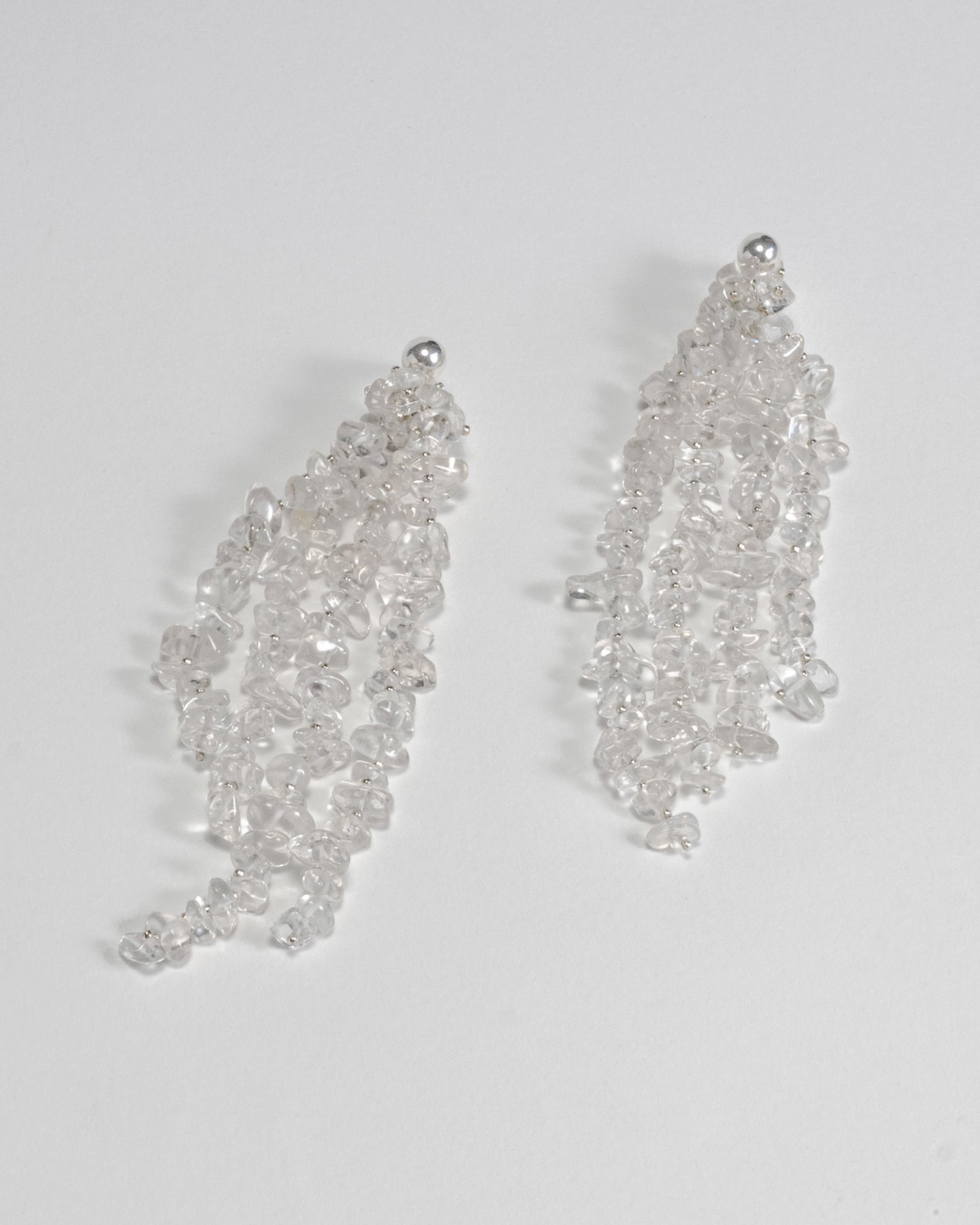 Long chunky dangling earrings featuring jagged clear quartz stones with silver hooks, 10 cm in length, offering bold and elegant design.