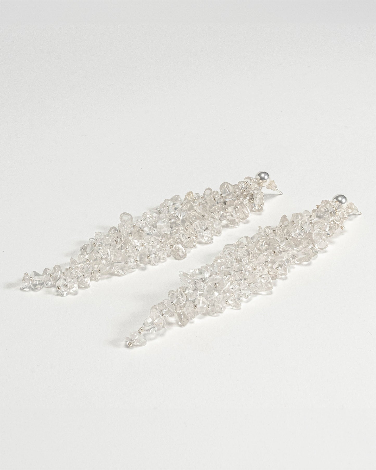 Long chunky dangling earrings featuring jagged clear quartz stones with silver hooks, 10 cm in length, offering bold and elegant design.