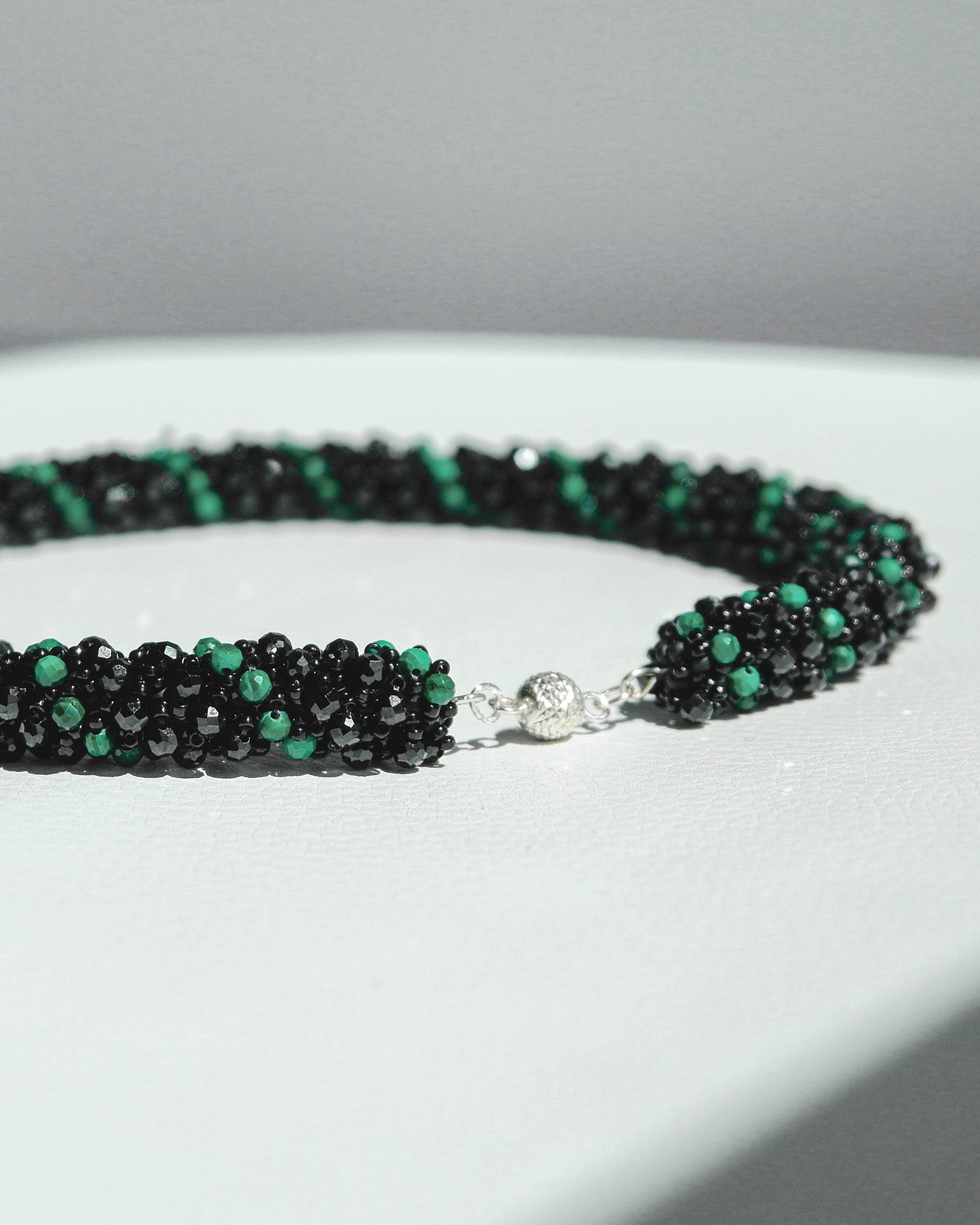 Malachite and spinel statement necklace featuring vibrant green malachite and black spinel pearls, 38 cm long, with a silver magnetic clasp.