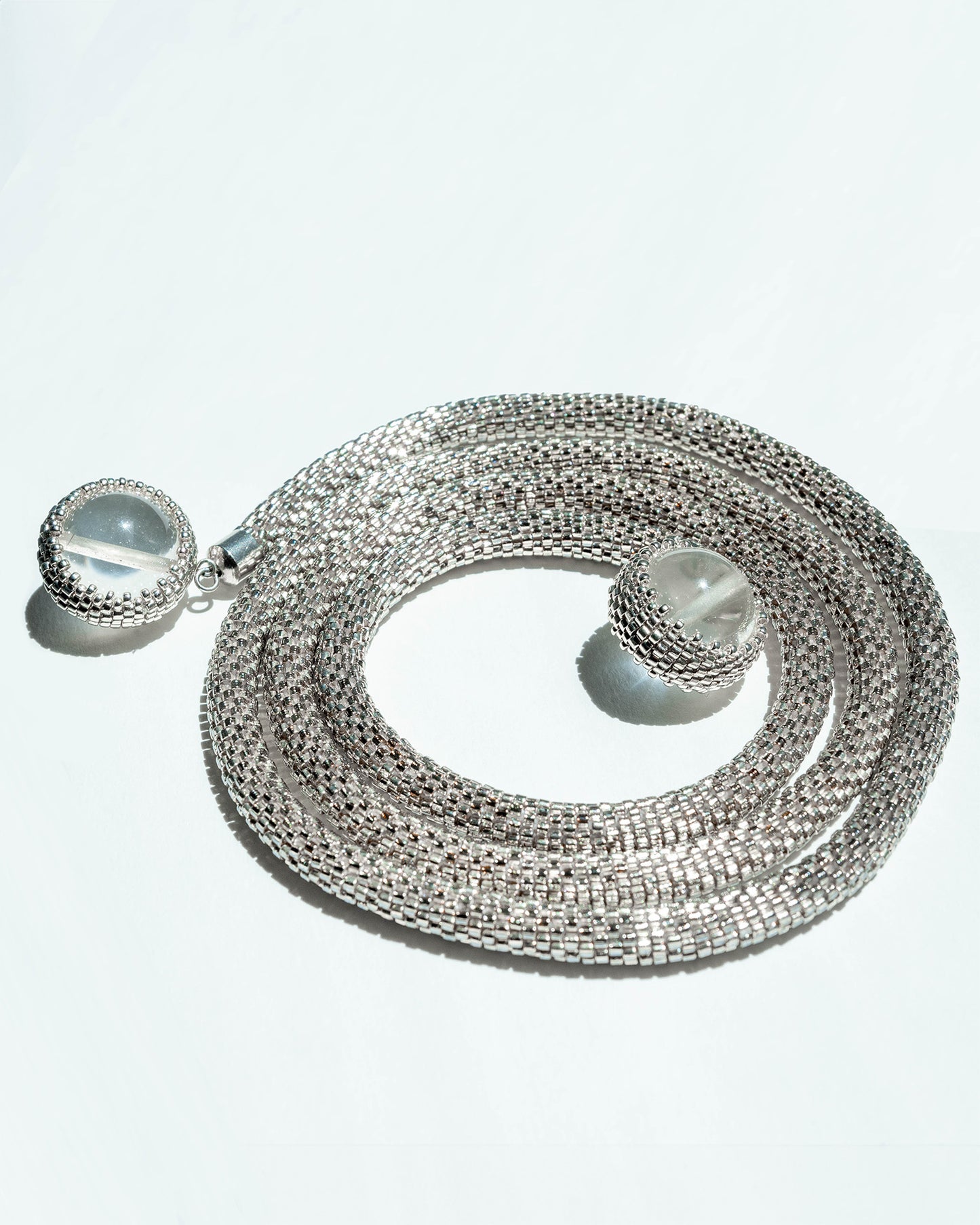 Long silver rope necklace adorned with 12 mm clear quartz stones and crafted from Japanese seed beads, 32 inches in length, offering versatile styling options.