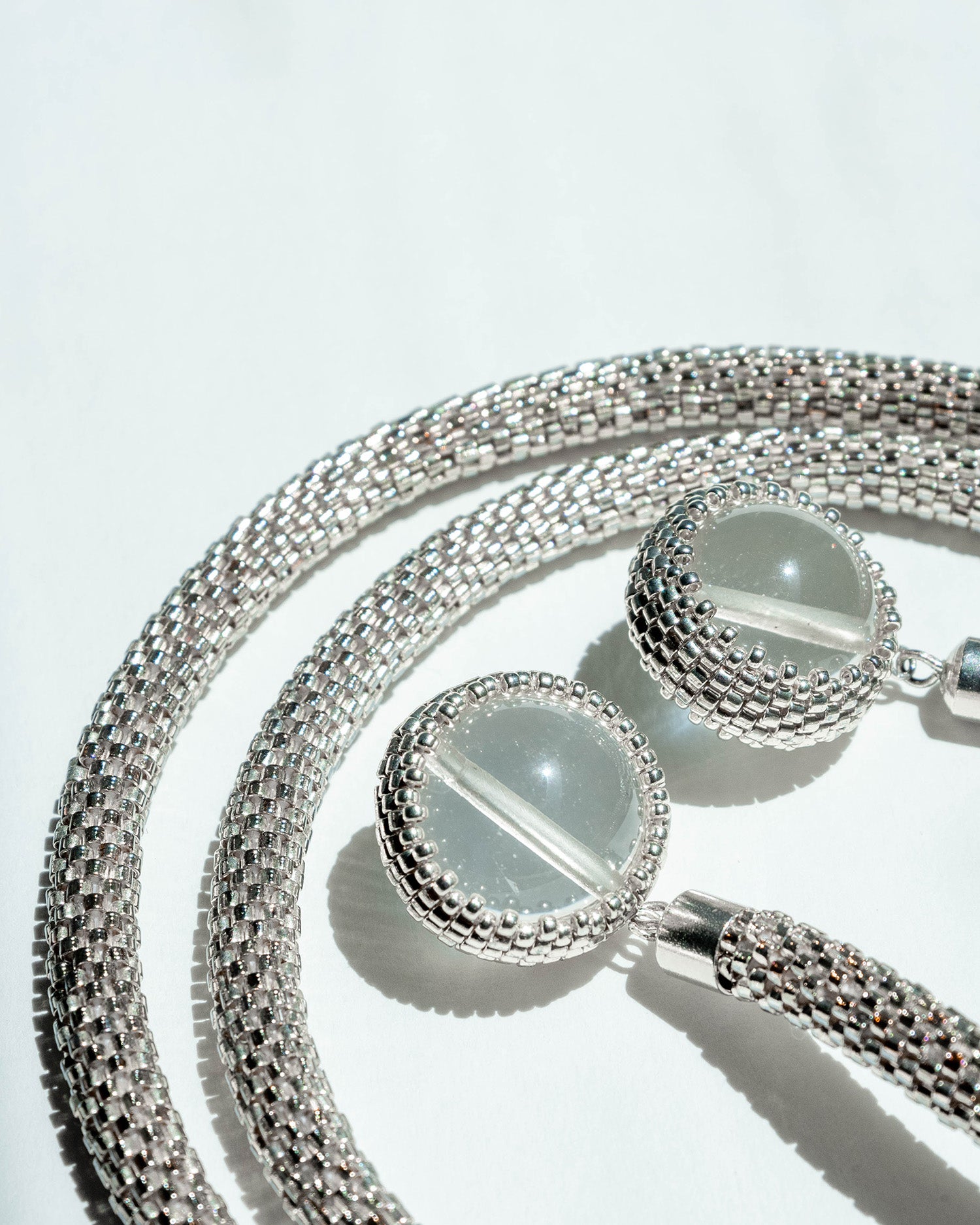 Long silver rope necklace adorned with 12 mm clear quartz stones and crafted from Japanese seed beads, 32 inches in length, offering versatile styling options.